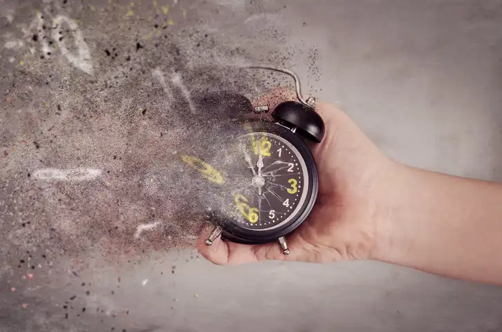 hand holding an alarm clock and fading away.